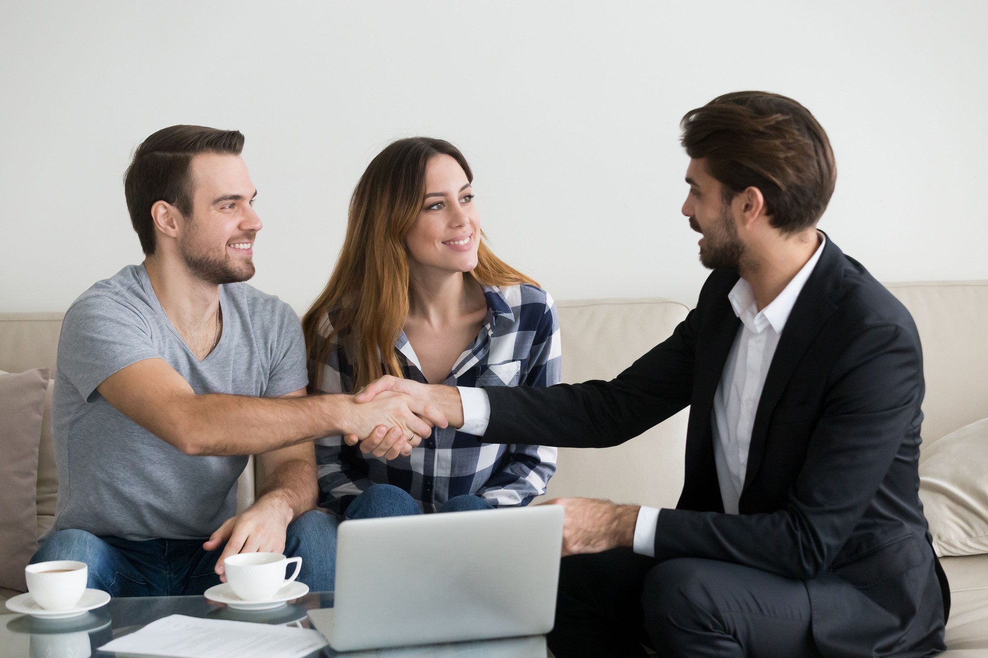 Happy family couple renters tenants handshaking Real Estate Agent landlord at meeting