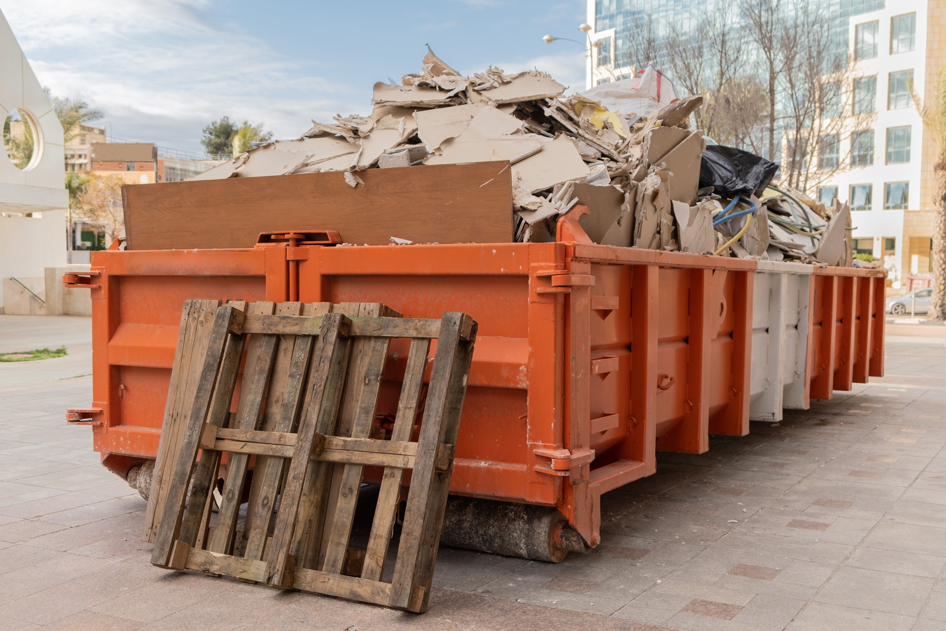 huge heap on metal Big  Overloaded dumpster waste container filled with construction waste, drywall and other rubble near a construction site."n